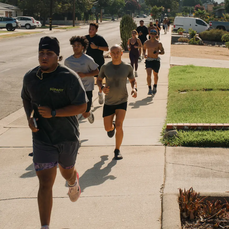 Pack of runners coming up a neighborhood sidewalk together on a bright morning