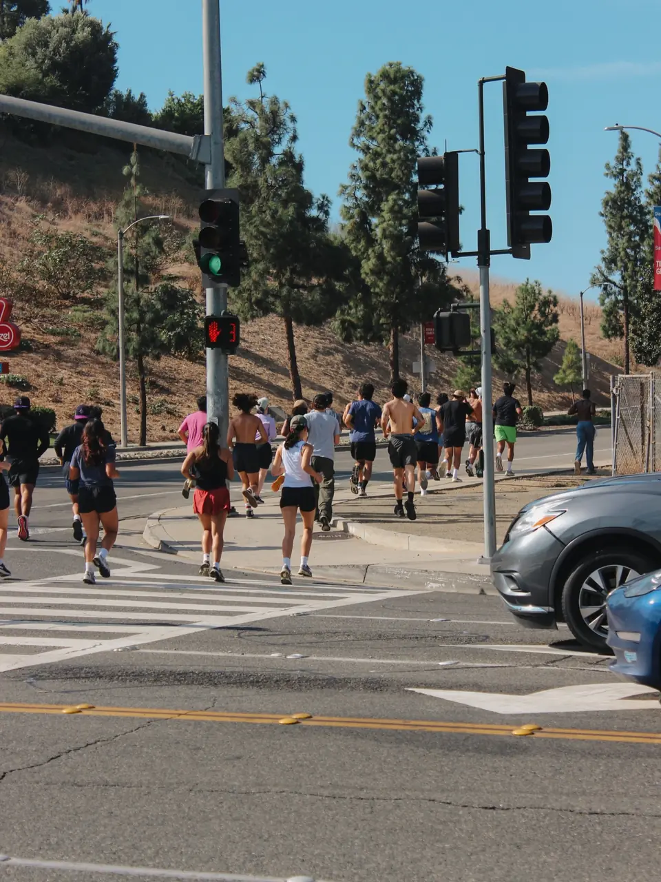 Pack of runners crossing a wide intersection at the light on a clear morning
