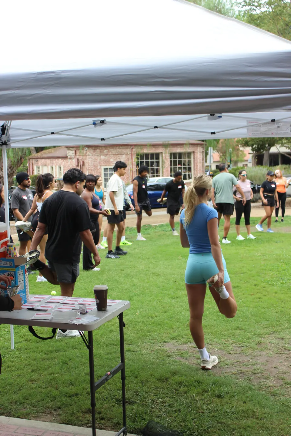 Runners stretching their quads on the grass next to the check in table